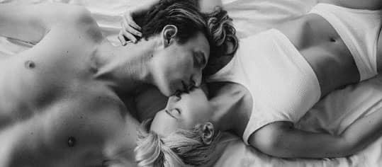 pareja de adultos dandose besos en la cama