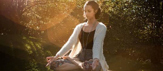 mujer meditando en medio del bosque